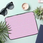 Light pink laptop sleeve with white horizontal stripes, offering a clean and minimalist design. the laptop sleeve on the table