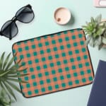 Infidu checkered beige and green laptop sleeve with a modern and colorful pattern. the laptop sleeve on the table