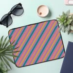 Colorful striped laptop sleeve with shades of blue, pink, yellow, and purple, offering a vibrant, playful design. the laptop sleeve on the table