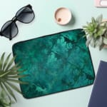 Infidu Dark Textured Teal-Green Laptop Sleeve with a smooth and elegant design. the laptop sleeve on the table