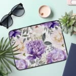 Elegant floral laptop sleeve with purple flowers and green leaves on a soft, light background. the laptop sleeve on the table