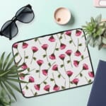 Infidu Floral Pink & Green Laptop Sleeve with pink flowers and green stems on a white background, offering protection and style. the laptop sleeve on the table