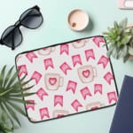 Light laptop sleeve with pink heart, ribbon, and beige mug pattern on a light background. the laptop sleeve on the table