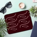 Infidu Maroon Laptop Sleeve with Heart & Wave Pattern design, featuring hearts and dotted wave lines in light colors against a maroon background. the laptop sleeve on the table