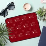 Red laptop sleeve with a playful white heart pattern on a bold red background, designed by digital artists for style and protection. the laptop sleeve on the table