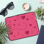 Infidu pink laptop sleeve with heart designs and dotted lines in shades of pink and purple. the laptop sleeve on the table