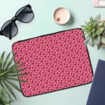 Pink laptop sleeve with a red heart pattern on a light surface. the laptop sleeve on the table