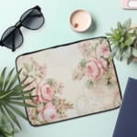 Elegant soft pink floral vintage laptop sleeve with light pink roses and green leaves on a pale background, designed for laptop protection. the laptop sleeve on the table