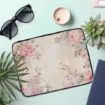 Elegant soft pink floral vintage laptop sleeve with light pink roses and green leaves on a pale background, designed for laptop protection. the laptop sleeve on the table