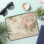 Infidu Vintage Floral Pastel Laptop Sleeve with pink and white flowers on light pastel background. Elegant design for laptop protection. the laptop sleeve on the table