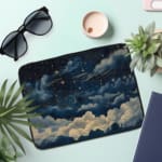 Infidu laptop sleeve with dreamy night sky design, featuring clouds and stars in dark blue and white tones. the laptop sleeve on the table