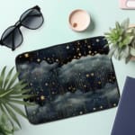 Rainy night sky laptop sleeve with stars, clouds, and a dark blue background. the laptop sleeve on the table