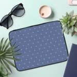 Simple blue laptop sleeve with white polka dots for a clean and stylish design. the laptop sleeve on the table