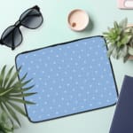 Simple blue laptop sleeve with white polka dots for a clean and stylish design. the laptop sleeve on the table