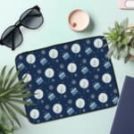 Infidu Dark Blue Winter Snowflake & Gift Laptop Sleeve with festive snowflakes, gifts, and a holiday design. the laptop sleeve on the table