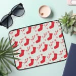 Infidu Christmas laptop sleeve with red stockings and holly berries on a white background, adding a festive touch for the holidays. the laptop sleeve on the table