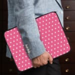 Light Pink laptop sleeve with a repeating white star pattern, shown against a bright background. the person holding the sleeve