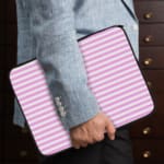 Light pink laptop sleeve with white horizontal stripes, offering a clean and minimalist design. the person holding the sleeve