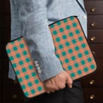 Infidu checkered beige and green laptop sleeve with a modern and colorful pattern. the person holding the sleeve