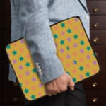 Infidu Green and Pink Star Pattern Laptop Sleeve with small green and pink stars on a light green background, displayed on a desk. the person holding the sleeve