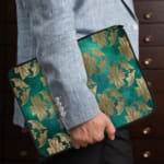 Elegant floral teal-blue laptop sleeve with beige and gold flowers, offering stylish protection for your laptop. the person holding the sleeve