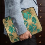 Infidu Beige Floral Design Laptop Sleeve with blue and teal flowers on a beige background. the person holding the sleeve