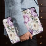 Infidu Elegant Purple Floral Laptop Sleeve featuring large purple flowers and green leaves on a light-colored background. the person holding the sleeve