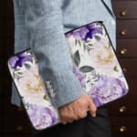 Elegant floral laptop sleeve with purple flowers and green leaves on a soft, light background. the person holding the sleeve