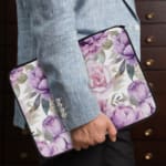 Infidu Elegant Floral Laptop Sleeve with purple and pink flowers, green leaves, and a soft white background, offering stylish laptop protection. the person holding the sleeve