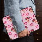 Infidu Romantic Heart & Floral Print Laptop Sleeve with pink hearts and flower bouquets on a white background. the person holding the sleeve