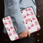 Infidu pink & white laptop sleeve with coffee cups, sofas, and hearts design on a white background. the person holding the sleeve