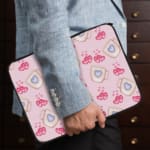 Infidu Light Pink Laptop Sleeve with Mug & Heart Print Design featuring small mugs with blue hearts and pink heart prints. the person holding the sleeve