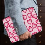 Infidu Pink Heart Pattern Laptop Sleeve with a playful design of large, evenly spaced pink hearts on a light pink background. the person holding the sleeve