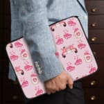 Infidu pink & white laptop sleeve with coffee cups, sofas, and hearts design on a white background. the person holding the sleeve