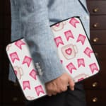 Light laptop sleeve with pink heart, ribbon, and beige mug pattern on a light background. the person holding the sleeve