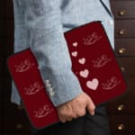 Infidu Maroon Heart & Angel Pattern Laptop Sleeve with white hearts and angel figures on a maroon background. the person holding the sleeve