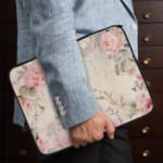 Elegant soft pink floral vintage laptop sleeve with light pink roses and green leaves on a pale background, designed for laptop protection. the person holding the sleeve