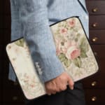 Infidu Vintage Floral Pastel Laptop Sleeve with pink and white flowers on light pastel background. Elegant design for laptop protection. the person holding the sleeve