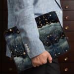 Rainy night sky laptop sleeve with stars, clouds, and a dark blue background. the person holding the sleeve