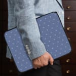 Simple blue laptop sleeve with white polka dots for a clean and stylish design. the person holding the sleeve