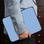 Simple blue laptop sleeve with white polka dots for a clean and stylish design. the person holding the sleeve