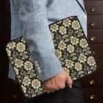 Infidu laptop sleeve with gold floral pattern on a black background. the person holding the sleeve