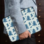 White laptop sleeve with a blue tree pattern for a nature-inspired look. the person holding the sleeve