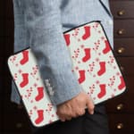 Infidu Christmas laptop sleeve with red stockings and holly berries on a white background, adding a festive touch for the holidays. the person holding the sleeve