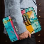 Infidu Colorful Abstract Laptop Sleeve featuring bright pink, blue, yellow, and black colors with stripes and dots on a vibrant design. the person holding the sleeve