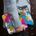 Infidu Modern Abstract Laptop Sleeve featuring bright colors like pink, blue, yellow, and black with geometric shapes and lines. the person holding the sleeve