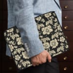 Infidu Black & Gold Floral Laptop Sleeve with a black background and detailed white floral pattern, featuring a secure zip closure. the person holding the sleeve