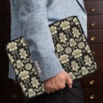 Black laptop sleeve with white floral pattern, detailed and symmetrical, for a bold and classic look the person holding the sleeve