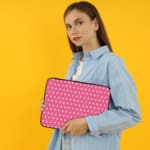 Light Pink laptop sleeve with a repeating white star pattern, shown against a bright background. the person holding the sleeve