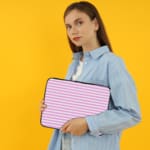 Light pink laptop sleeve with white horizontal stripes, offering a clean and minimalist design. the person holding the sleeve